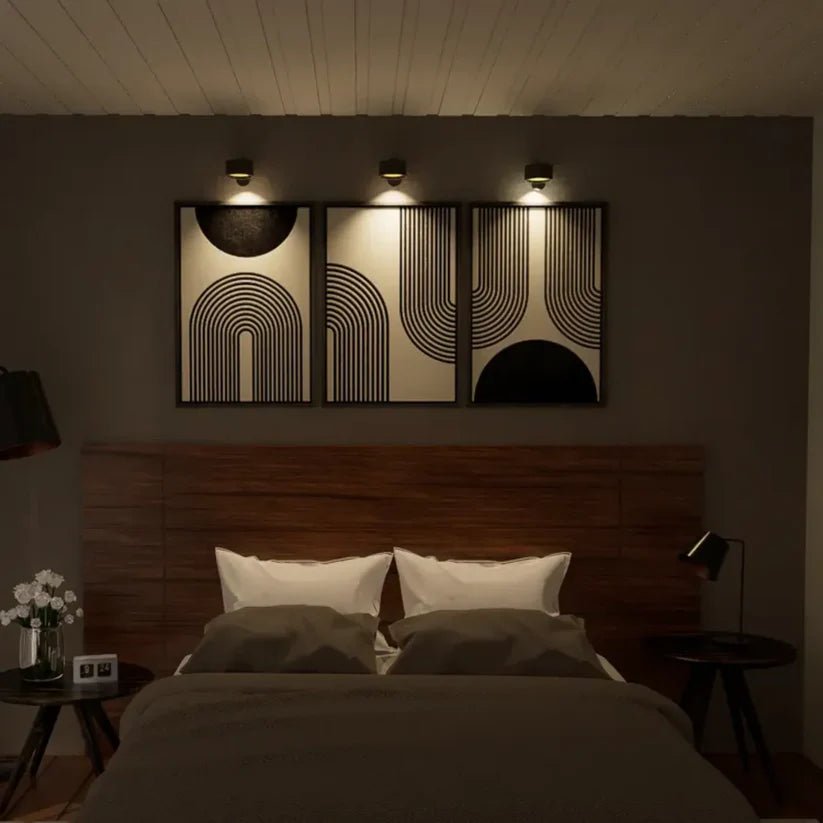 A stylish bedroom featuring a wooden headboard, white pillows, and modern geometric wall art illuminated by infinity wall lamps.