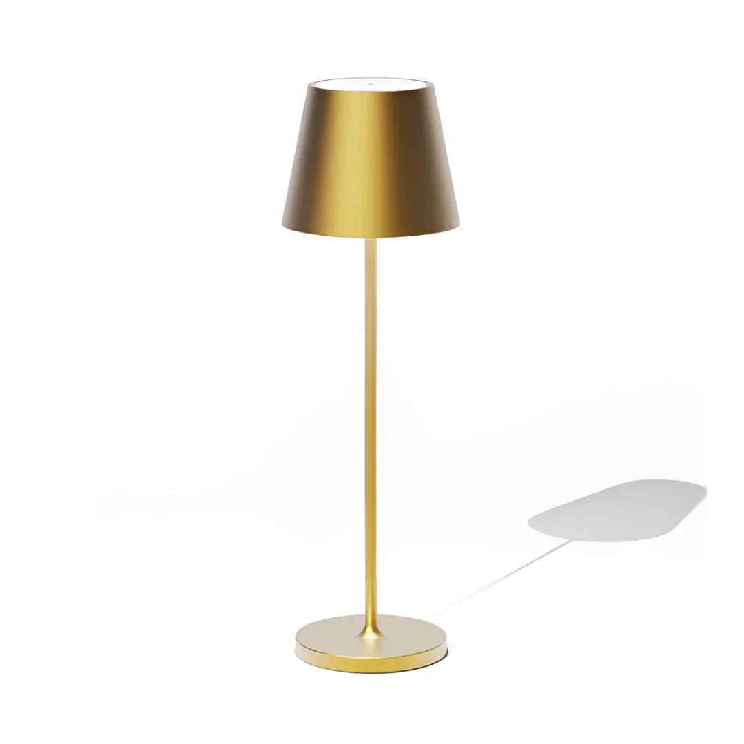 Modern wireless gold table lamp with a conical shade, standing on a circular base, casting a subtle shadow on a white background.