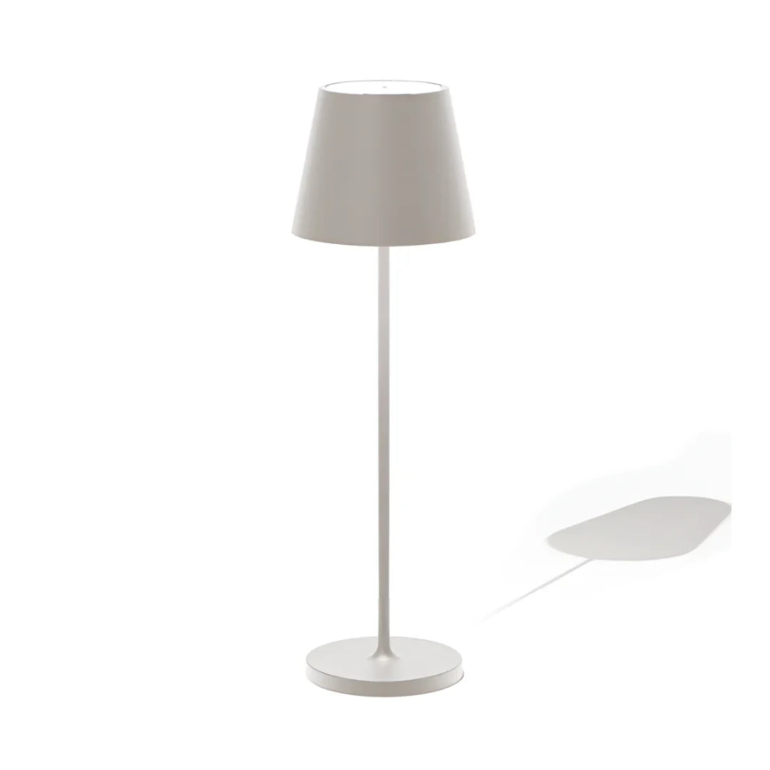 Modern wireless light gray table lamp with a conical shade, standing on a circular base, casting a subtle shadow on a white background.