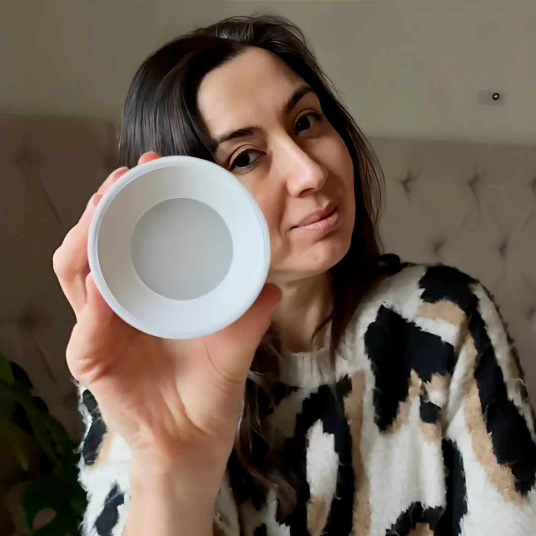 Woman holding a white infinity wall lamp in front of her face