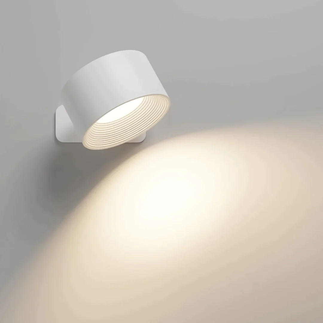 A stylish white wireless wall lamp directs warm light onto a gray wall, enhancing the ambiance with a soft glow and modern design.