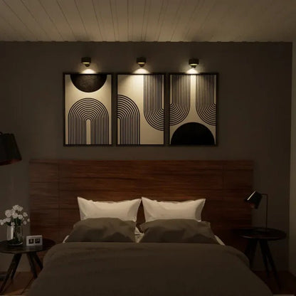 A stylish bedroom featuring a wooden headboard, white pillows, and modern geometric wall art illuminated by infinity wall lamps.
